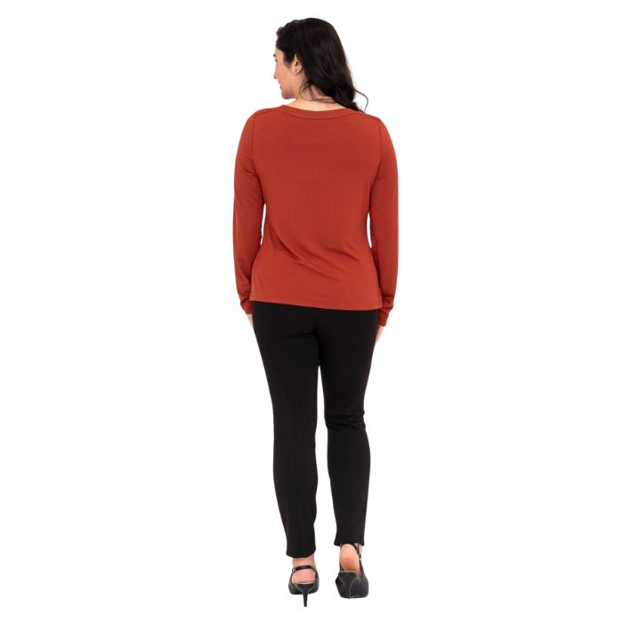 female model wearing mona cuprum orange long sleeve top and nadia black pants back view on white background