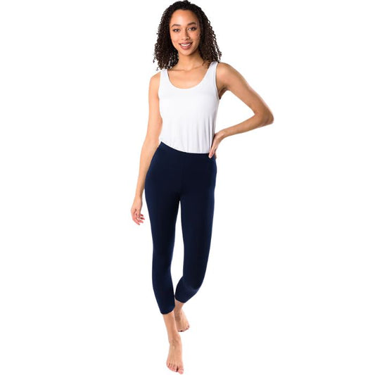 female model wearing ink blue suri capri length leggings and white cindy tank top front view on white background