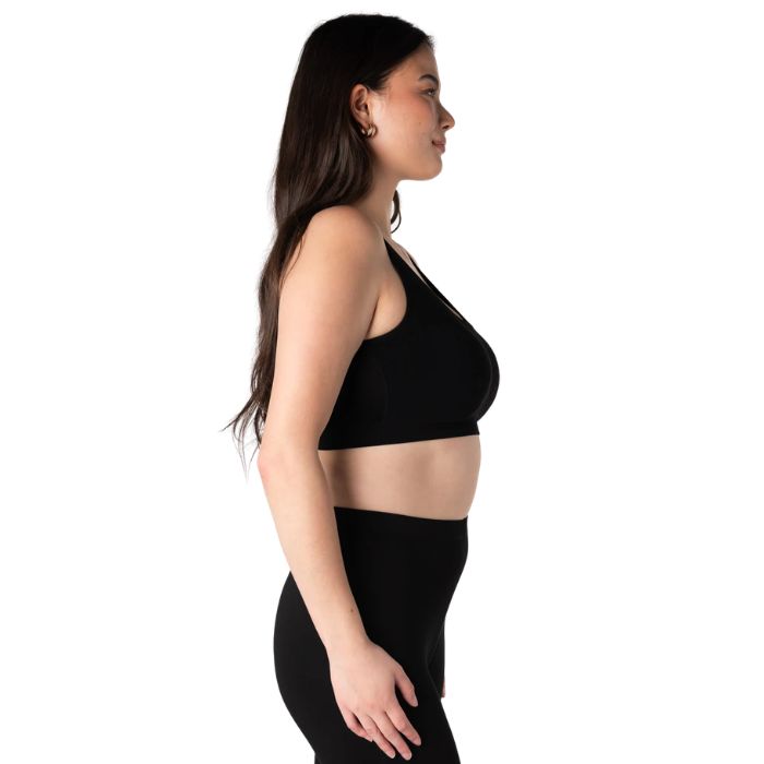 female model wearing black essential bralette side view on white background