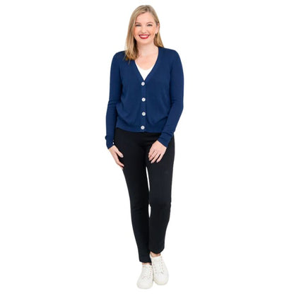 female model wearing indigo blue jessica button up cardigan sweater, white reanna tank top and black nadia pants front view on white background