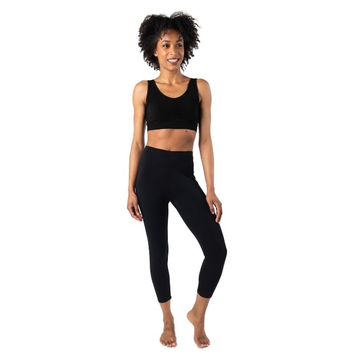 female model wearing black suri capri leggings and black terrera essential bralette front view on white background